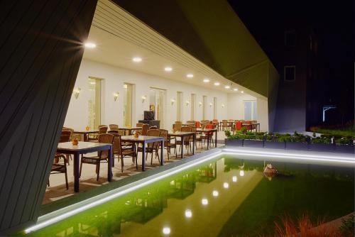 a restaurant with tables and chairs and a swimming pool at Anna Hotel in Budapest