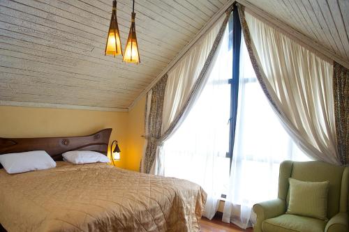 a bedroom with a bed and a chair and a large window at The Great Rift Valley Lodge & Golf Resort in Naivasha