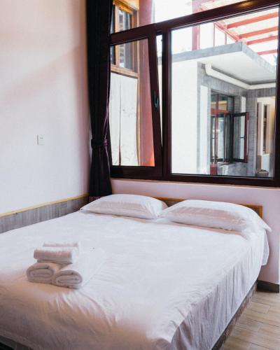 a bed with two towels on it in a room with a window at Chez Ina & Jasee in Miyun