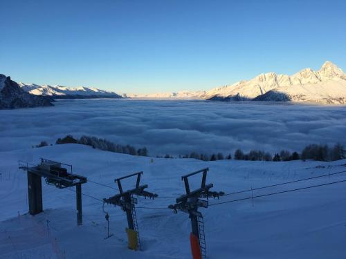 a view of a snow covered mountain with clouds at Restaurant Fleschboden in Rosswald