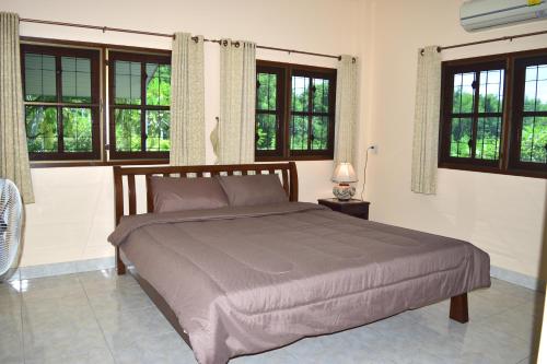 a bedroom with a large bed with windows at Kate House Bangsaphan in Bang Saphan