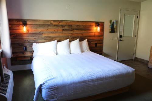 a bedroom with a large white bed with a wooden wall at Hidden Canyon Retreat in Baker