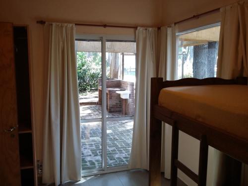1 dormitorio con 1 cama y puerta corredera de cristal en Complejo Reliqua Dunamar Claromeco en Balneario Claromecó