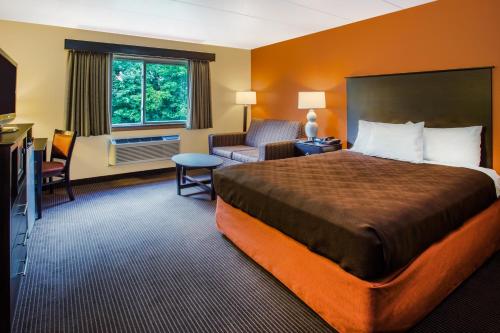 a hotel room with a bed and a chair at AmericInn by Wyndham Menomonie in Menomonie
