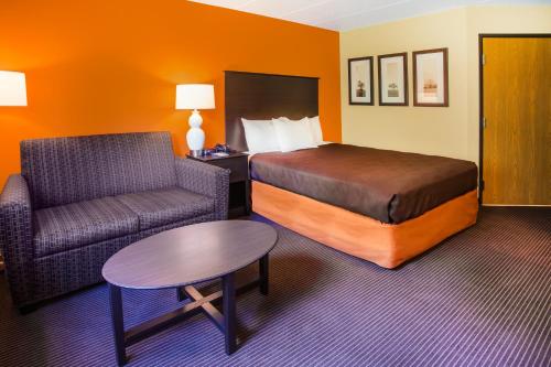 a hotel room with a bed and a couch and a table at AmericInn by Wyndham Menomonie in Menomonie
