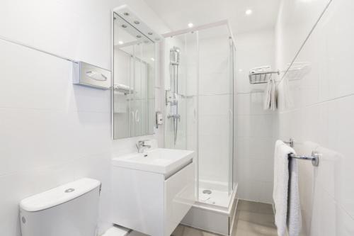 Un baño blanco con inodoro y lavabo. en Hotel Bastille Secret, en París