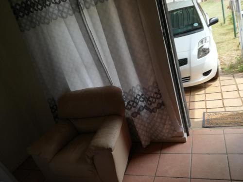 Habitación con silla y ventana con coche en MulMas Guest House, en Pretoria