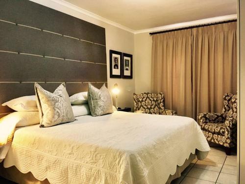 a bedroom with a large bed and a chair at Centre-Ville Guest House in Franschhoek