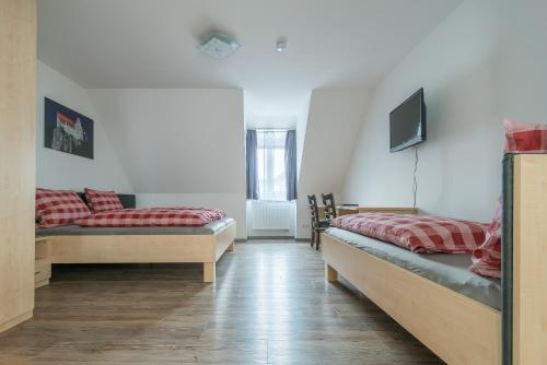 ケールハイムにあるAnitas Altstadtpensionのベッド2台、壁掛けテレビが備わる客室です。