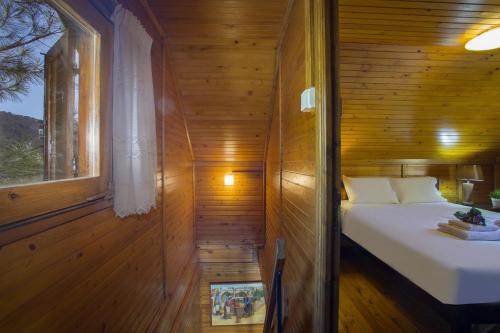 a small bedroom with a bed in a wooden wall at Ricky Chalet Near Troodos in Spilia