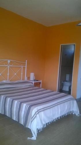 a bedroom with a large bed with an orange wall at HM San Jose in San José