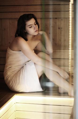 a woman sitting on a table in a sauna at Villa Elise Park Pension in Stronie Śląskie