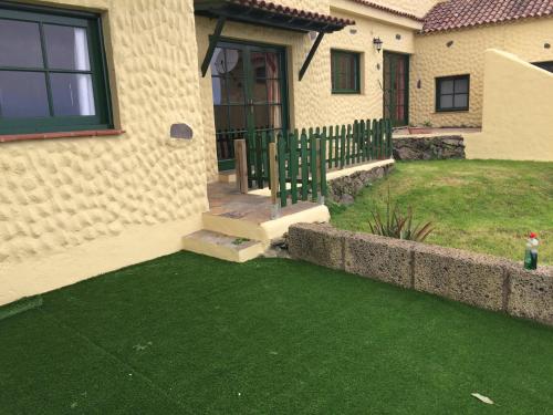 a house with a fence and a yard with green grass at Casitas Las Uvas y las Viñas in Los Realejos