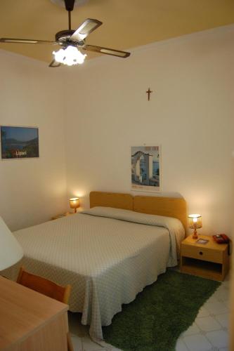 a bedroom with a bed and a cross on the wall at Hotel Villa Augustus in Lipari