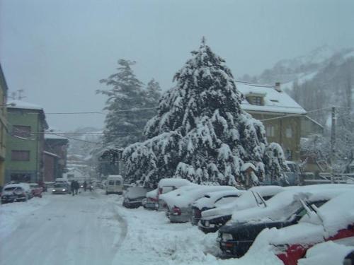 a snow covered christmas tree on a snowy street at Hotel Peña Pandos in Felechosa