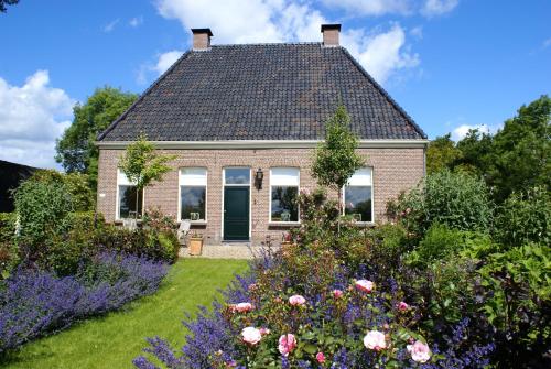 a house with a garden with flowers in front of it at De Heerlijkheid Ruinerwold in Ruinerwold