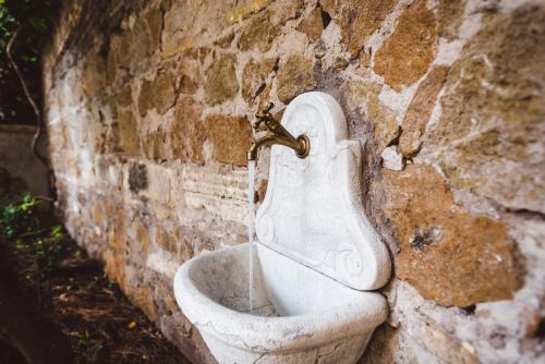 a white toilet in a brick wall with a faucet at Relais Circo Massimo in Rome