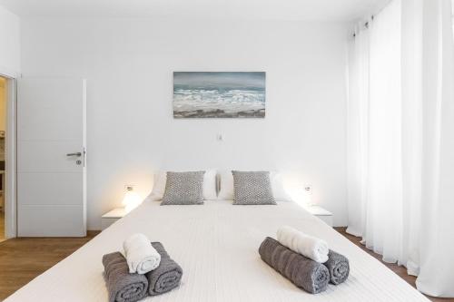 a white bedroom with a large bed with towels on it at Central Suite Rijeka in Rijeka