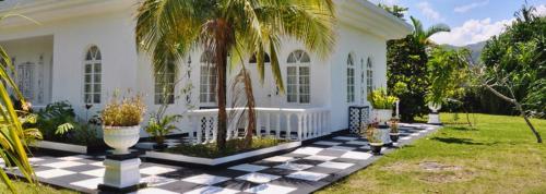 a white house with a checkered floor and palm trees at Jamaica Palace Hotel in Port Antonio