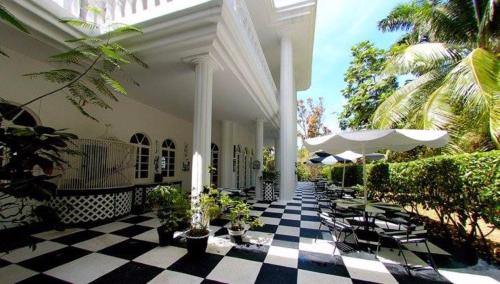 a patio with tables and chairs and umbrellas at Jamaica Palace Hotel in Port Antonio