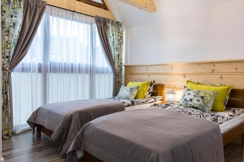 two beds in a room with a window at Apartament PAJO III Ski RESORT in Zakopane
