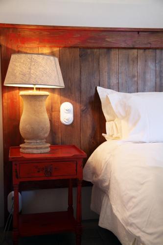 une lampe sur une table rouge à côté d'un lit dans l'établissement Les Bergeries d'Arone, à Piana