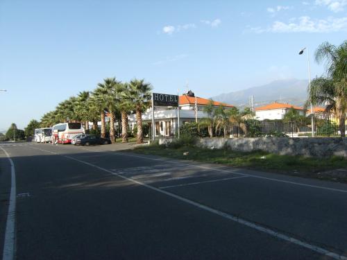 an empty street with a hotel and palm trees at King's House Hotel Resort in Mascali