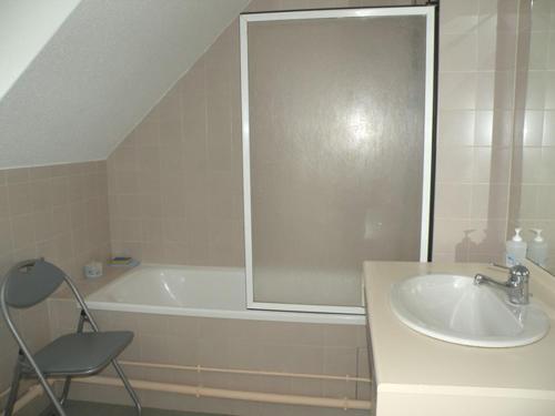 La salle de bains est pourvue d'une baignoire, d'un lavabo et d'une chaise. dans l'établissement Marina Apartment, à La Forêt-Fouesnant