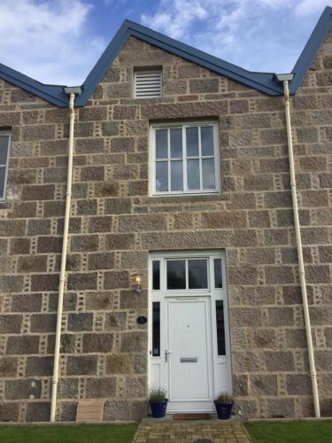 a brick house with a white door at The Sidings Inverurie in Inverurie