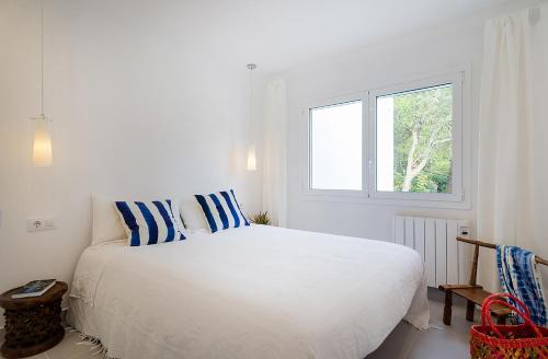 een witte slaapkamer met een groot bed met blauwe en witte kussens bij Azteka Blue 2 Bed Apartment Calella de Palafrugell in Calella de Palafrugell