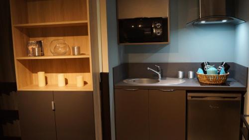 une petite cuisine avec un évier et un micro-ondes dans l'établissement Au Saint Martin 2, à Cholet