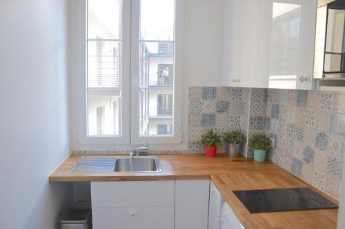 cocina con fregadero y ventana en Longchamp Apartment, en París