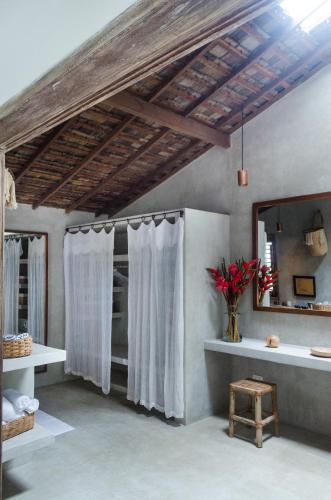 a bathroom with white curtains and a mirror at Casa Lola in Trancoso