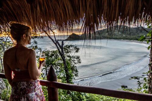 a woman holding a glass of wine looking at the ocean at Morgan's Rock in San Juan del Sur