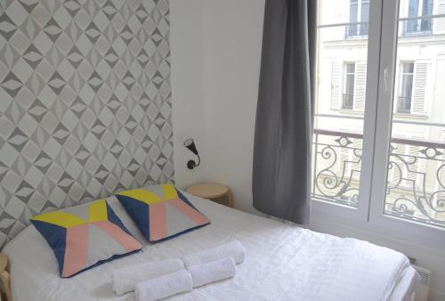 1 dormitorio con 1 cama con ventana y colcha blanca en Longchamp Apartment, en París