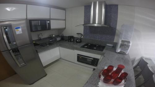 a kitchen with stainless steel appliances and red bottles on the counter at Carneiros Beach Resort - Flat 2 Quartos in Tamandaré