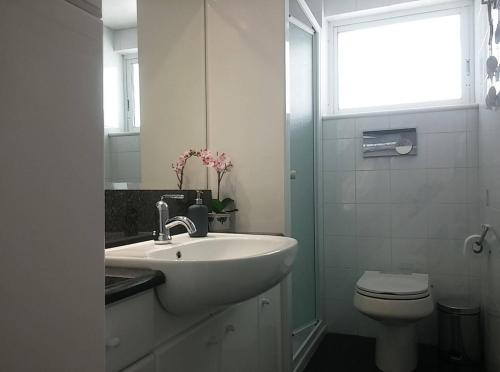 a white bathroom with a sink and a toilet at Overlooking the blue sea in Rafina