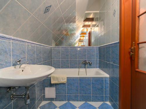 Hotel Flora Dolní Mísečky في Dolni Misecky: حمام من البلاط الأزرق مع حوض استحمام وحوض استحمام