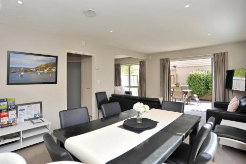 a living room with a dining table and chairs at Regents 94B - Christchurch Holiday Homes in Christchurch