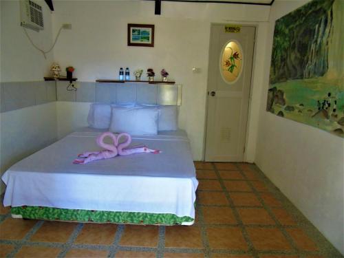 a room with a bed with a pink ribbon on it at Phaidon Beach Resort in Pandan