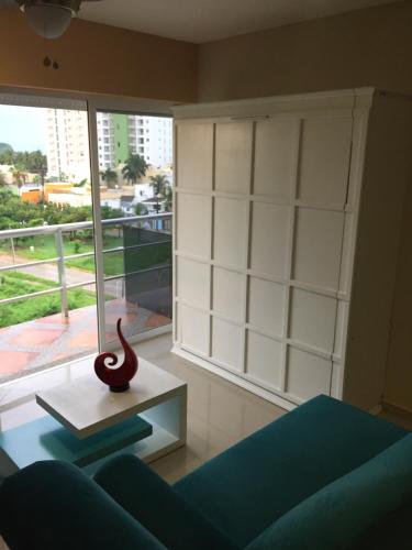 a living room with a blue couch and a large window at Playa y alberca en Zona Marina in Mazatlán