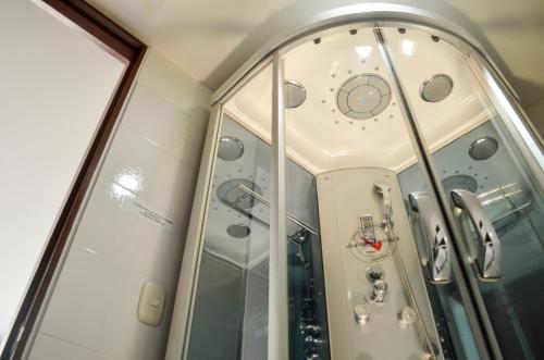 a glass walled shower with a clock in it at Hotel Tarigua Ocaña in Ocaña