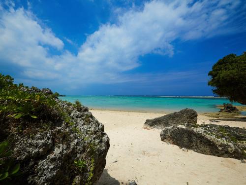une plage avec quelques rochers et l'océan dans l'établissement Cottage Sea Wind Nakijin, à Nakijin