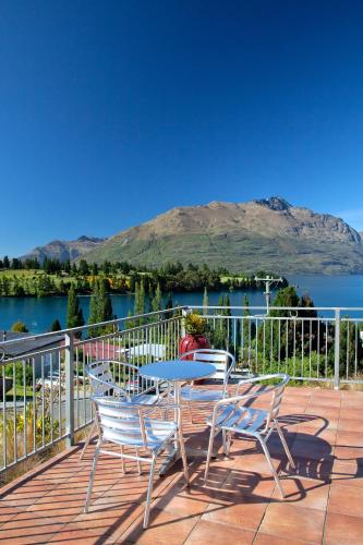 a table and chairs on a deck with a view of the water at Alexis Motel & Apartments in Queenstown