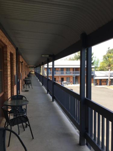 a patio area with chairs, tables, and umbrellas at Bega Downs Motor Inn in Bega