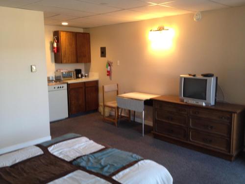 a room with a bed and a desk with a television at Departure Bay Motel in Nanaimo