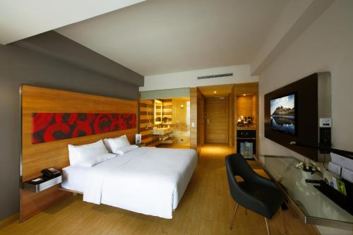 a bedroom with a large white bed and a flat screen tv at Novotel Pekanbaru in Pekanbaru
