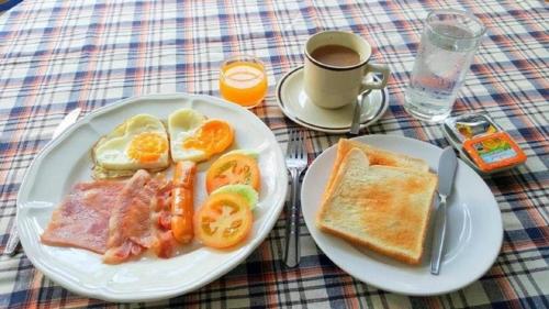 uma mesa com um prato de comida para o pequeno-almoço e uma chávena de café em Chomdoi House Hotel em Chiang Mai