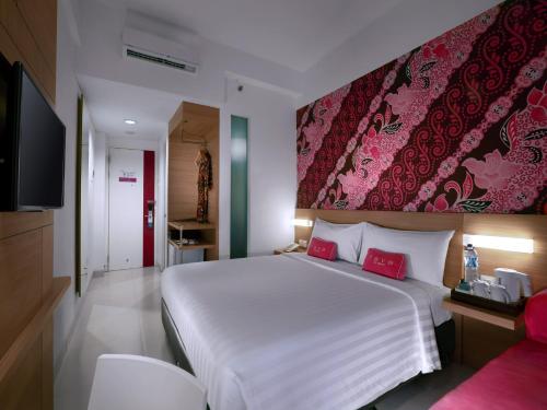 a bedroom with a large white bed and a red wall at favehotel Malioboro - Yogyakarta in Yogyakarta