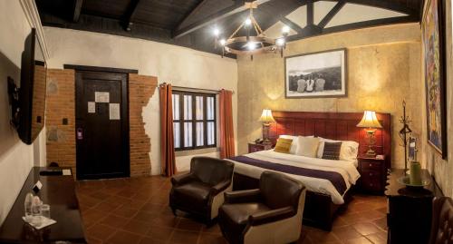 a bedroom with a bed and two chairs in it at Los Olivos Boutique Hotel Antigua Guatemala in Antigua Guatemala